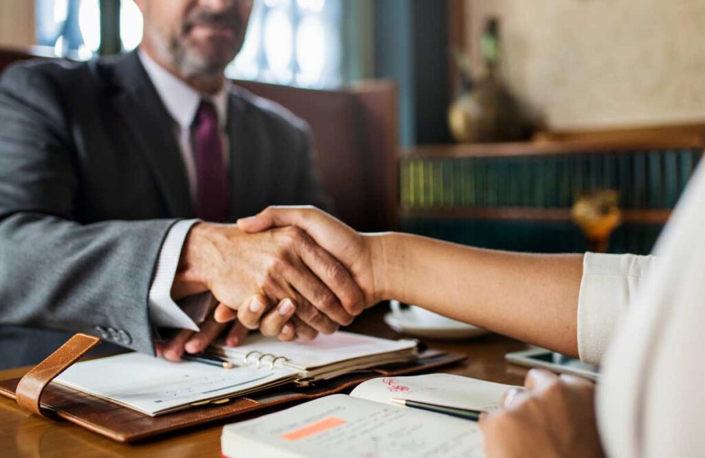 A professional handshake between a TLR Law Firm representative and a client during a meeting in Manitoba, symbolizing guidance and trust in the executor role process.
