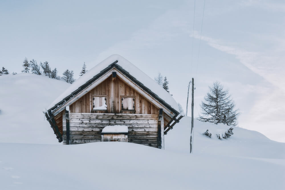 Snow-covered wooden cottage in rural Manitoba during winter, illustrating seasonal property insurance and legal planning considerations for cottage owners with guidance from TLR Law.