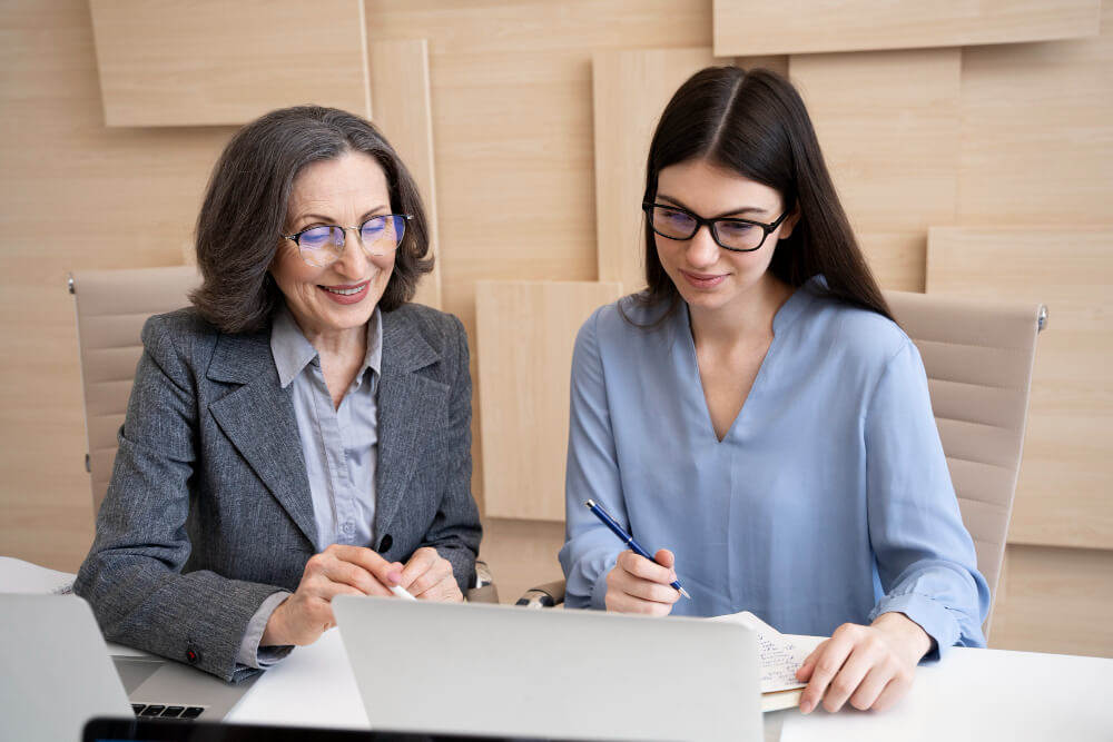 Two women reviewing and signing legal documents during a consultation, illustrating independent legal advice for financial agreements with TLR Law in Manitoba.