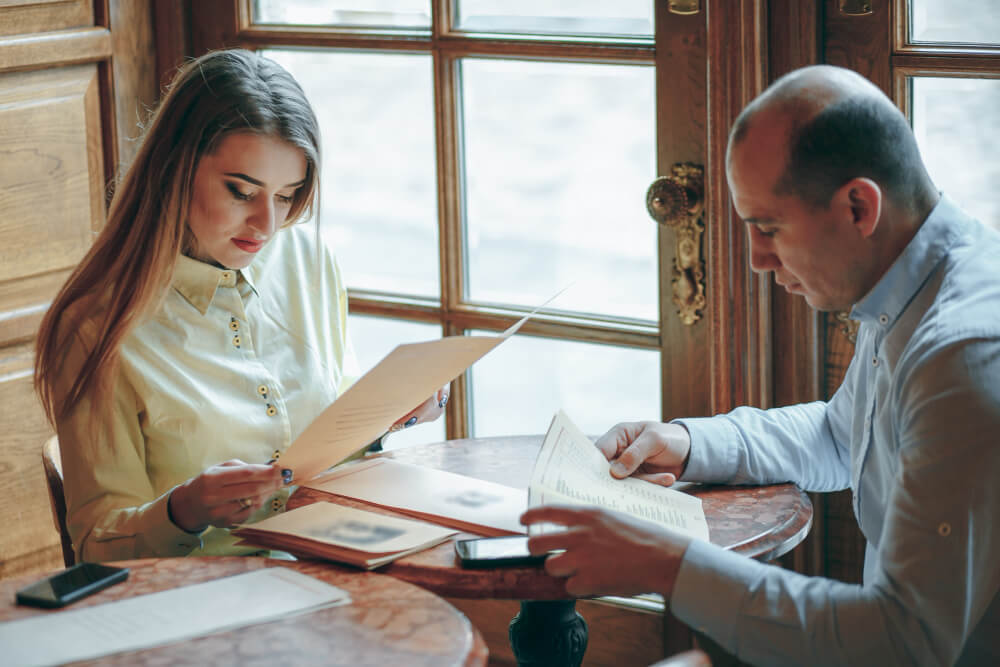Spouses reviewing legal documents together at a table, representing wills and estate planning decisions even when one partner is more ready to start, with guidance from TLR Law in Manitoba.