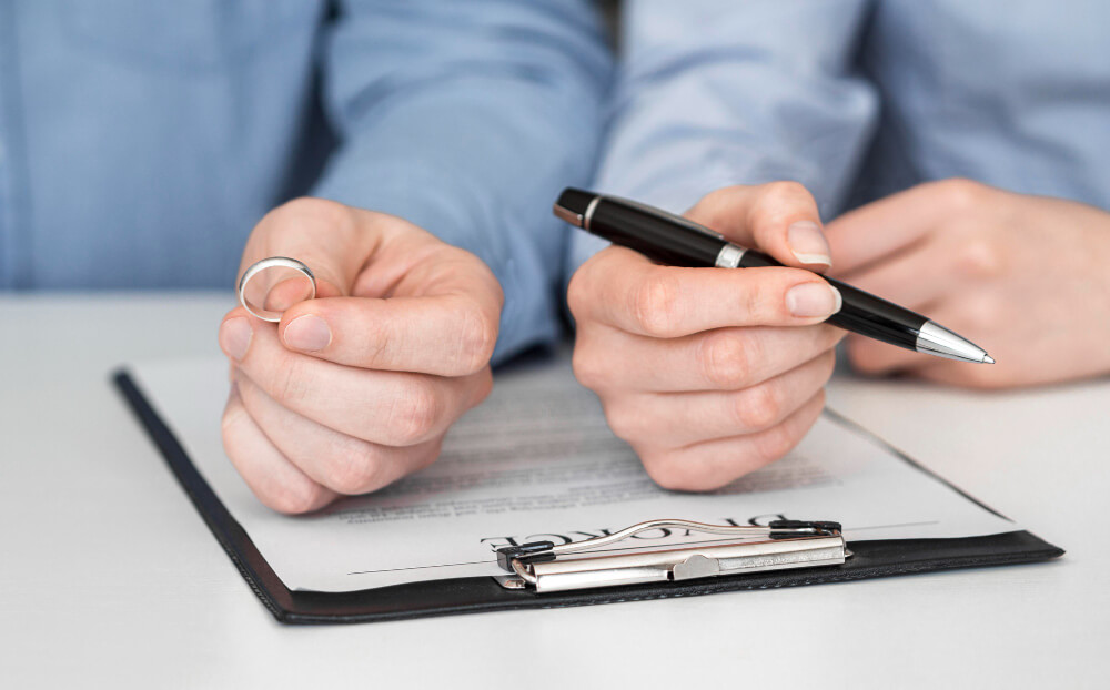 Person holding a wedding ring while reviewing legal documents, symbolizing updating wills and powers of attorney after separation with guidance from TLR Law in Manitoba.