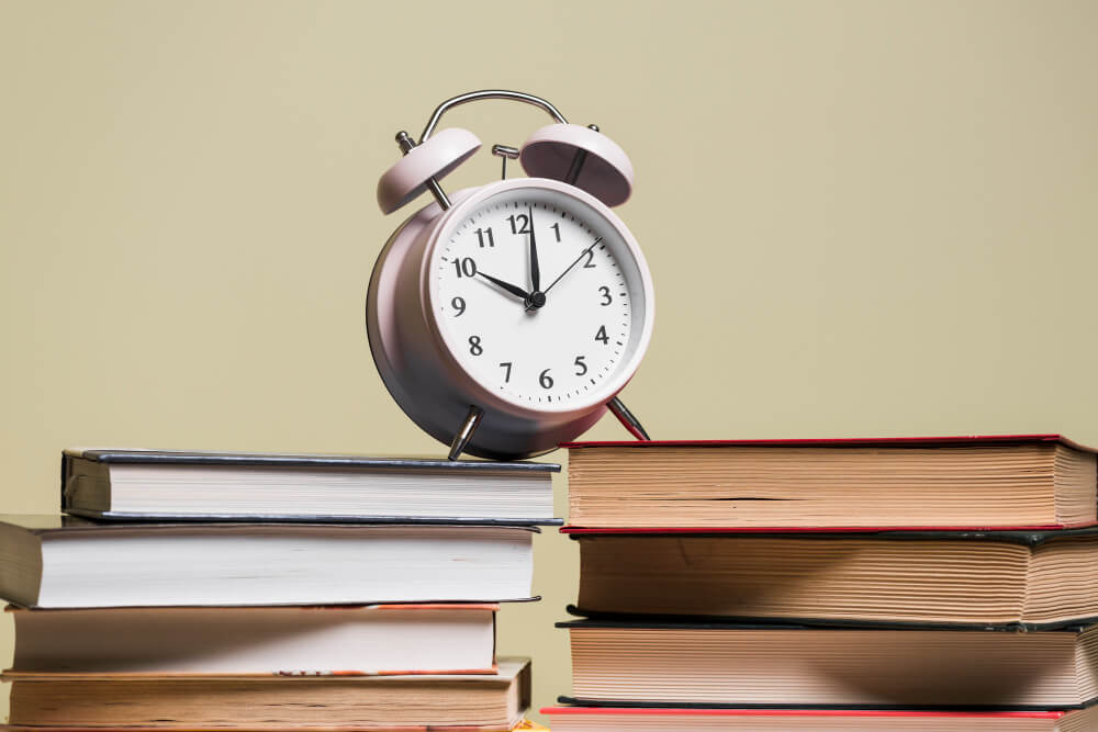 Alarm clock resting on stacked books, representing corporate recordkeeping deadlines and minute book maintenance for TLR Law in Manitoba.