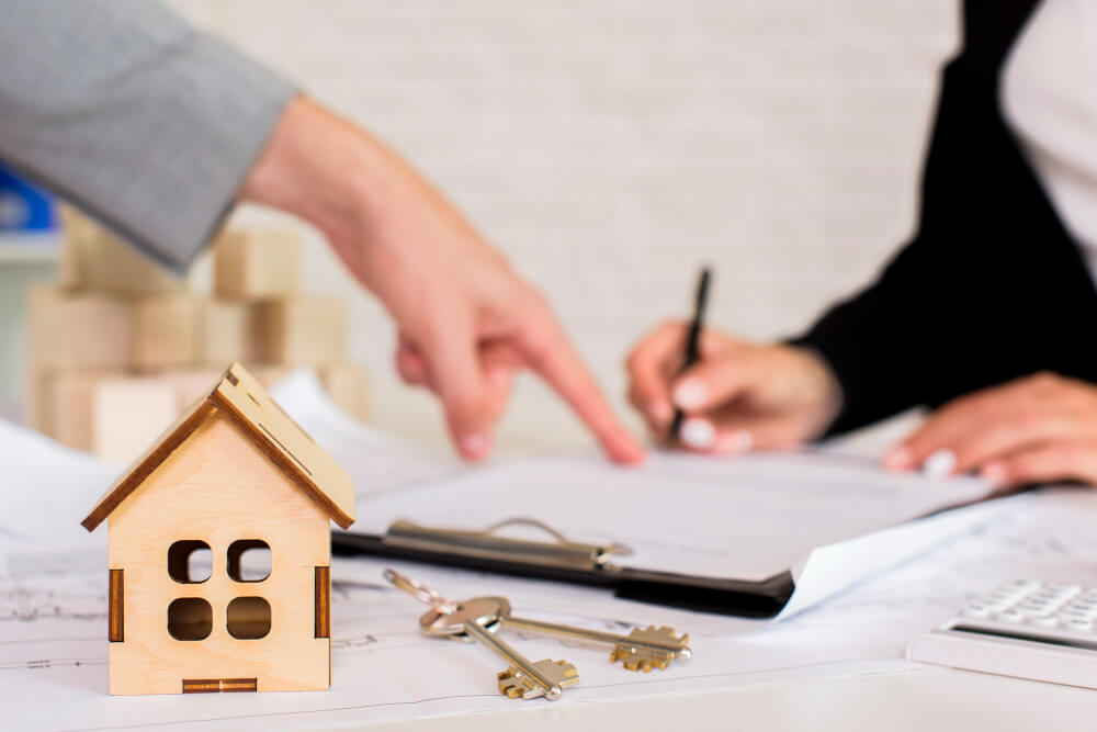 House model, keys, and legal documents during an estate consultation, representing the process of inheriting and transferring a home with guidance from TLR Law in Manitoba.