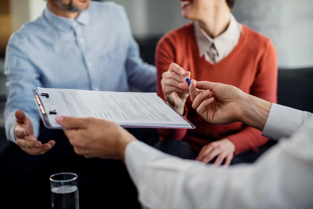 Couple reviewing legal documents with a professional, representing executor responsibilities and estate administration after a death in Manitoba.