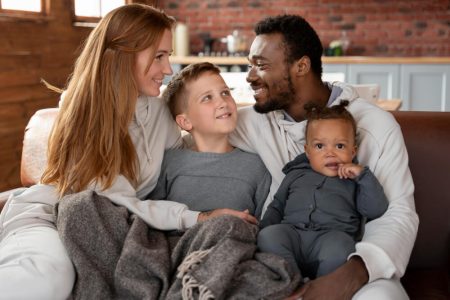 Blended family with parents and children sitting together at home, symbolizing estate planning and inheritance considerations for blended families, with guidance from TLR Law in Manitoba.