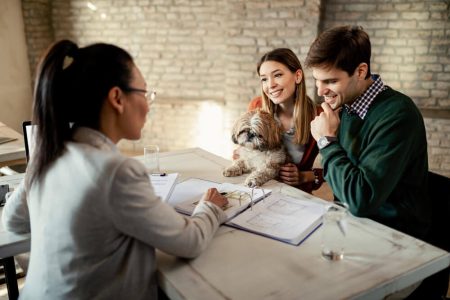 Couple meeting with a lawyer to discuss home purchase paperwork and down payment planning, reflecting guidance on gifting funds to adult children from TLR Law in Manitoba.