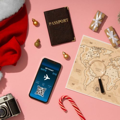 Holiday travel essentials including passport, flight ticket on smartphone, world map, and Christmas decorations, representing family travel planning and legal preparedness in Manitoba with TLR Law.