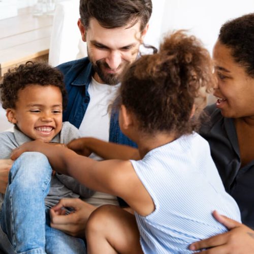 Blended family laughing together at home, symbolizing unity and love while planning wills and estates in Manitoba with TLR Law.