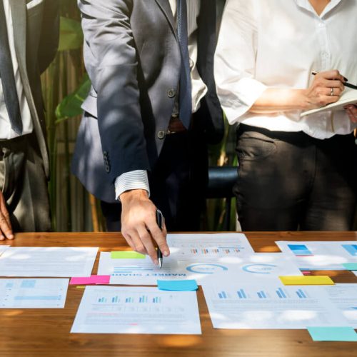 Business professionals in Manitoba reviewing financial charts and documents during a small business succession planning meeting, illustrating legal and operational strategies for succession planning in Manitoba.