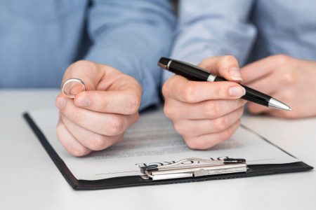 Person holding a wedding ring while reviewing legal documents, symbolizing updating wills and powers of attorney after separation with guidance from TLR Law in Manitoba.