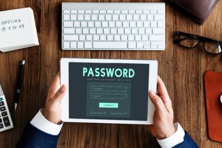 Person holding a tablet showing a password login screen at a desk, representing digital assets, account access, and online legacy planning with guidance from TLR Law in Manitoba.