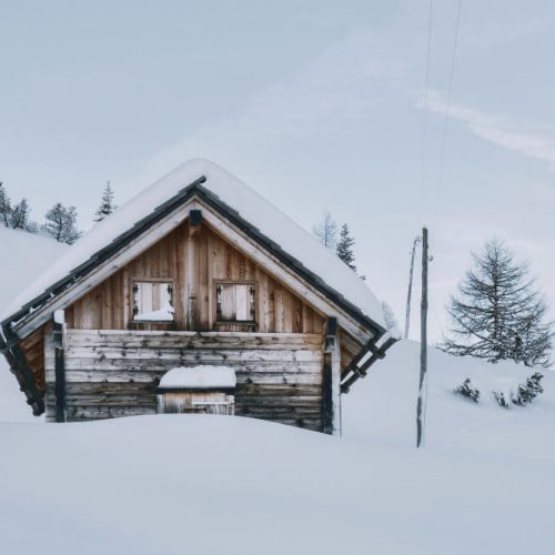 Snow-covered wooden cottage in rural Manitoba during winter, illustrating seasonal property insurance and legal planning considerations for cottage owners with guidance from TLR Law.