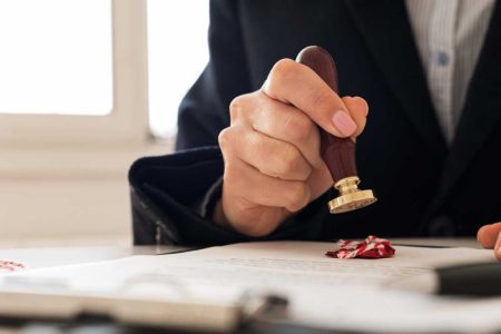 A close-up of a notary stamping a legal document with a wax seal, symbolizing official authorization. This image represents the importance of Power of Attorney (POA) in estate planning. Blog post by TLR Law, serving Winnipeg.